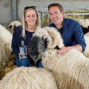 Tanya and Tim Spittle with some of their sheep - and a bottle of the vodka they make from their flock’s milk. Credit: Glos News