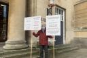 County resident Keith Smith pictured holding placards outside Shire Hall on March 14, 2023. FREE TO USE FOR ALL PARTNERS. CREDIT: Carmelo Garcia