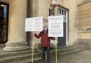County resident Keith Smith pictured holding placards outside Shire Hall on March 14, 2023. FREE TO USE FOR ALL PARTNERS. CREDIT: Carmelo Garcia