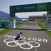 A worker paints Olympic rings at the finish line of the BMX racing track as preparations continue for the 2020 Summer Olympics, Tuesday, July 20, 2021, at the Ariake Urban Sports Park in Tokyo. (AP Photo/Charlie Riedel).